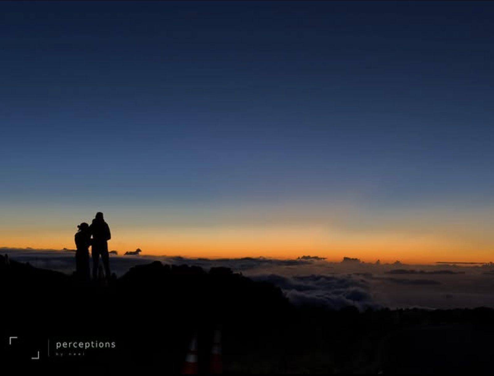 Two figures silhouetted above the clouds at first light